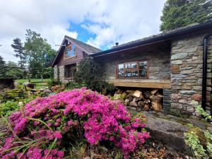 a stone house with pink flowers in front of it at Loch Lomond shore Boat House in Balmaha