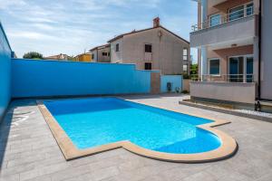 einen Pool im Hinterhof mit blauer Wand in der Unterkunft APARTMENTS EKI in Banjole