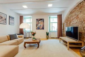 ein Wohnzimmer mit einem Sofa und einem Fernseher und einer Ziegelwand in der Unterkunft Priestranný apartmán Moja Marína® v srdci Štiavnice in Banská Štiavnica