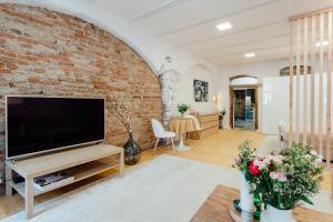 ein Wohnzimmer mit einem großen TV und einer Ziegelwand in der Unterkunft Priestranný apartmán Moja Marína® v srdci Štiavnice in Banská Štiavnica + 16 Fotos