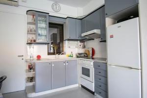 a kitchen with blue cabinets and a white refrigerator at Esperida Apartment by RentalsPro - Fourka Beach Halkidiki in Skala Fourkas