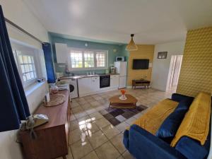 a living room with a blue couch and a kitchen at L'hacienda de Soubran, Le Gîte à Grand-mère, classé 4 étoiles in Soubran