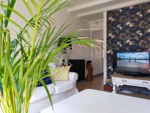 a living room with a white couch and a tv at Maison confortable à Lens proche du centre et du stade in Lens