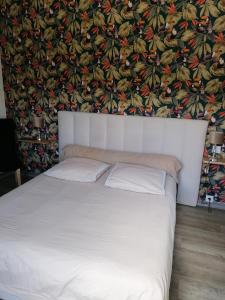 a bedroom with a white bed with a floral wallpaper at Moulin de brezal à 20 minute de la mer in Plounéventer