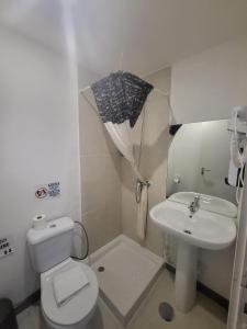 a bathroom with a toilet and a sink and an umbrella at What Else Guest House - Fatima in Fátima