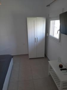 a bedroom with a white cabinet and a table at Villa Giotis Suite in Skala Sotiros