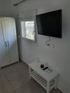 a living room with a table and a tv on the wall at Villa Giotis Suite in Skala Sotiros