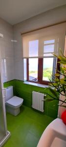 baño verde con aseo y ventana en Apartamento Rural Playa Foz - VISTAS AL MAR, en Foz