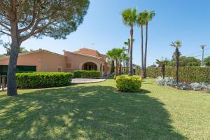 une maison avec des palmiers et une pelouse dans l'établissement Mulholland Villa, à Can Picafort