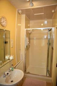 y baño con ducha, lavabo y reloj. en Wortley Cottage Guest House, en Wortley