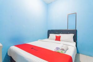 Schlafzimmer mit einem Bett mit einem roten Kissen und Handtüchern in der Unterkunft RedDoorz Syariah At Jl Pangeran Hidayatullah Cianjur in Cianjur