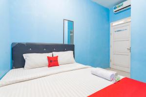 ein blaues Schlafzimmer mit einem Bett mit einem roten Kissen in der Unterkunft RedDoorz Syariah At Jl Pangeran Hidayatullah Cianjur in Cianjur