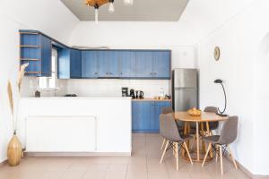 a kitchen with blue cabinets and a table and chairs at Ampelos Executive Houses in Pirgos