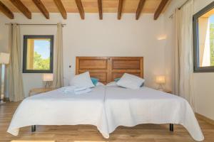 uma cama branca num quarto com duas janelas em Villa Pins em Porto Colom