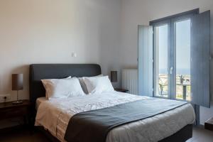 sypialnia z dużym łóżkiem i dużym oknem w obiekcie Ampelos Executive Houses w mieście Pirgos