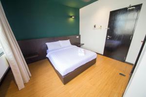 a bedroom with a white bed with a green wall at Room V Jalan Jenang by SECOMS in Batu Pahat