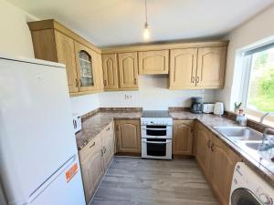 a kitchen with wooden cabinets and a white stove top oven at Trewebster in Crafthole