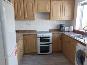 a kitchen with wooden cabinets and a white stove top oven at Trewebster in Crafthole