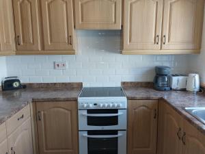 a kitchen with wooden cabinets and a stove top oven at Trewebster in Crafthole