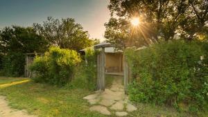 Un pequeño edificio en un campo con el sol brillando. en Clay House Banya, en Banya