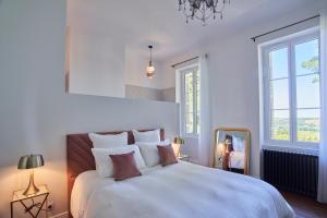a white bedroom with a large bed and a mirror at CHATEAU BELAIR-Séjour Prestige in Sainte-Croix-du-Mont