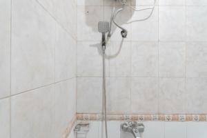 e bagno piastrellato bianco con doccia. di RedDoorz Plus At Hotel Sofia Pangandaran a Pangandaran