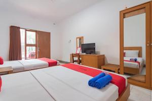 una camera d'albergo con due letti e una televisione di RedDoorz Plus At Hotel Sofia Pangandaran a Pangandaran