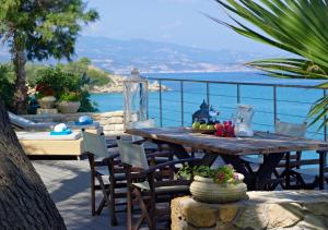 einen Holztisch und Stühle mit Meerblick in der Unterkunft Paradisso Beach Villas in Ammoudi