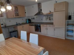 une cuisine avec des armoires blanches et une table avec des chaises dans l'établissement Ferienwohnung im Seidlerhof mit Terrasse, à Röhrnbach 34 autres photos