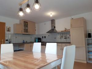 a kitchen with a wooden table and white chairs at Ferienwohnung im Seidlerhof mit Terrasse in Röhrnbach