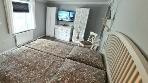 ein Schlafzimmer mit einem Bett, einer Kommode und einem TV in der Unterkunft Apartment Mai in Elmenhorst