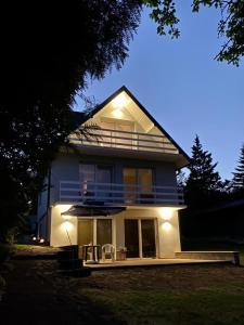 a large house with a porch with chairs and an umbrella at Dom Dwa Jeziora - Augustów in Augustów