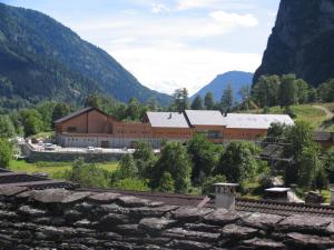 a large brown building with mountains in the background at Casa Vacanze La Meridiana in Baceno