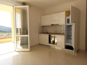 a kitchen with white cabinets and an open door at appartamento martina in Scarlino