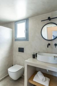 a bathroom with a sink and a toilet and a mirror at Ampelos Executive Houses in Pyrgos