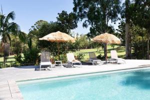 a group of chairs and umbrellas next to a pool at Coral villa in Byron Bay