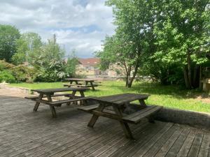 un grupo de mesas de picnic en una terraza de madera en le Châtelet, en La Chaux Neuve