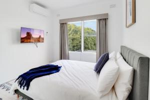 a bedroom with a bed with white sheets and a window at Highton Accommodation (Geelong) in Geelong