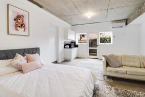 Highton Accommodation (Geelong) في جيلونج: غرفة نوم بيضاء مع سرير وأريكة