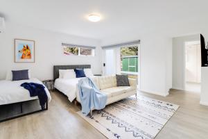 1 dormitorio blanco con 2 camas y sofá en Highton Accommodation (Geelong) en Geelong