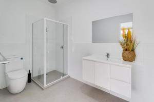 uma casa de banho branca com um chuveiro e um WC. em Highton Accommodation (Geelong) em Geelong
