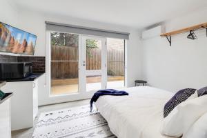 een witte slaapkamer met een bed en een raam bij Highton Accommodation (Geelong) in Geelong