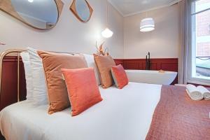 een slaapkamer met een bed met kussens en een bad bij Miss Marguerite Suite in Parijs