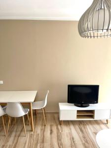 a dining room with a white table and a tv at Twentysix Apartment in Shkodër