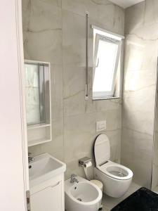 a white bathroom with a toilet and a sink at Twentysix Apartment in Shkodër