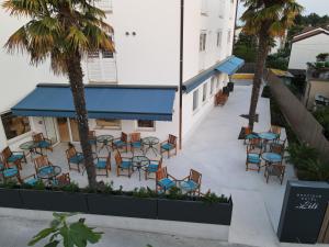 an outdoor patio with chairs and tables and palm trees at Boutique hotel Lili in Rovinj