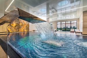 a large pool with a fountain in a building at Hotel Park Kajetany in Nadarzyn