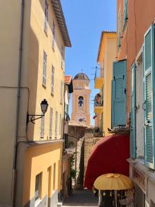 an alley with an umbrella and a clock tower at CHARMING APARTMENT NEAR THE BEACH in Villefranche-sur-Mer
