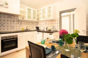 una cucina con armadi bianchi e un tavolo con fiori rosa di Happy Holiday Cascais - Garden a Cascais