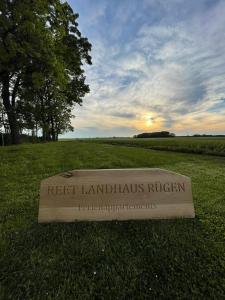 a sign in the grass with the sunset in the background at Reet Landhaus Rügen in Ummanz